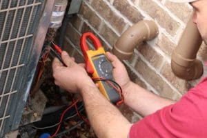 Kurt Zentner & Sons Plumbing & Heating technician checking the levels of an outdoor AC unit