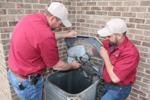 Technicians from Kurt Zentner & Sons Plumbing & Heating repairing an air conditioning unit