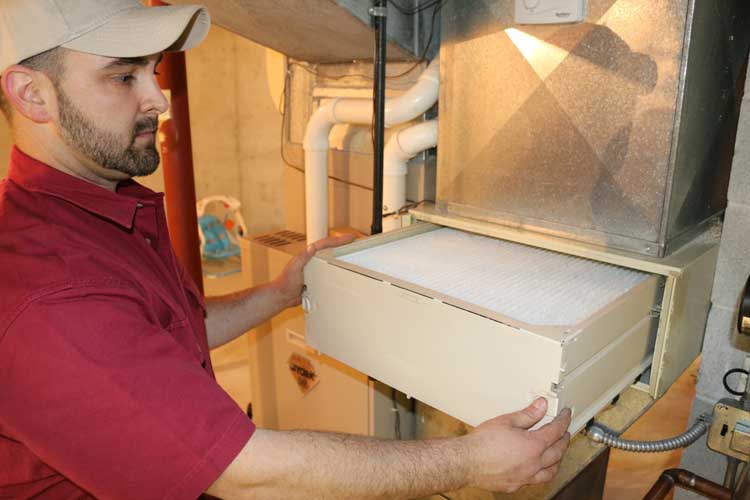 Kurt Zentner & Sons Plumbing & Heating technician replacing an air filter
